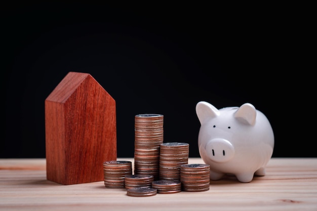 Pig piggy bank and Model house and coin stack on black background saving concept