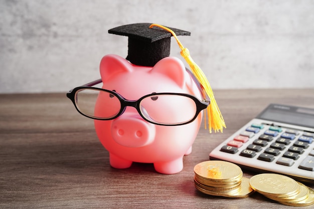 Pigging bank wearing eyeglass with coins and calculator saving bank education concept