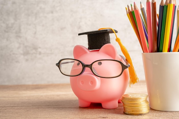 Pigging bank wearing eyeglass with colorful pencils saving bank\
education concept