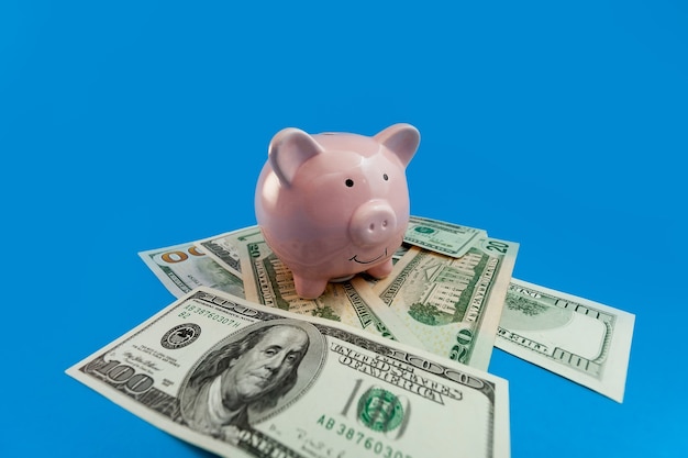Piggy bank on the background of US dollars banknotes on a blue background