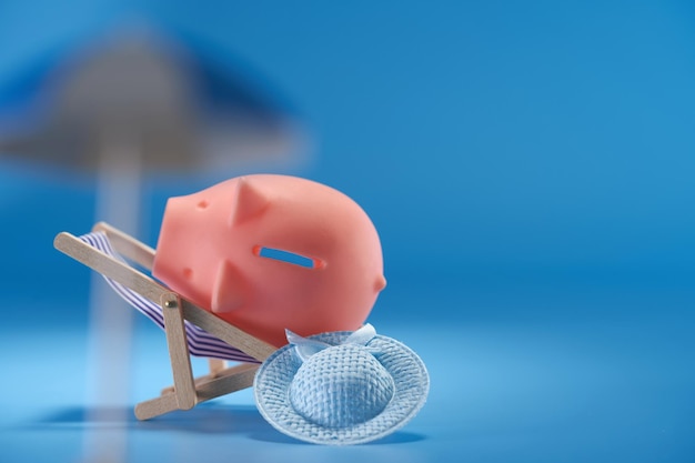 Piggy bank on beach chair against blue background
