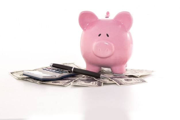 Piggy bank beside calculator on dollars 