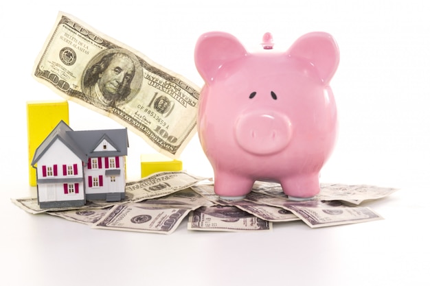 Piggy bank beside graph and miniature house