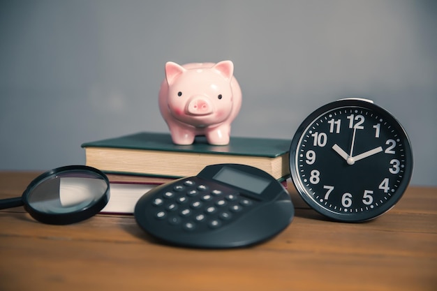 Piggy bank on the book and calculator on tablexA