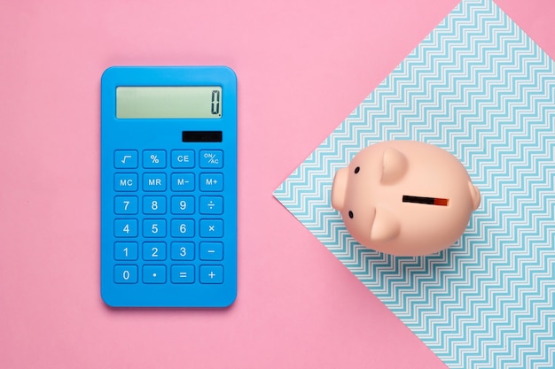 Piggy bank and calculator on blue pink