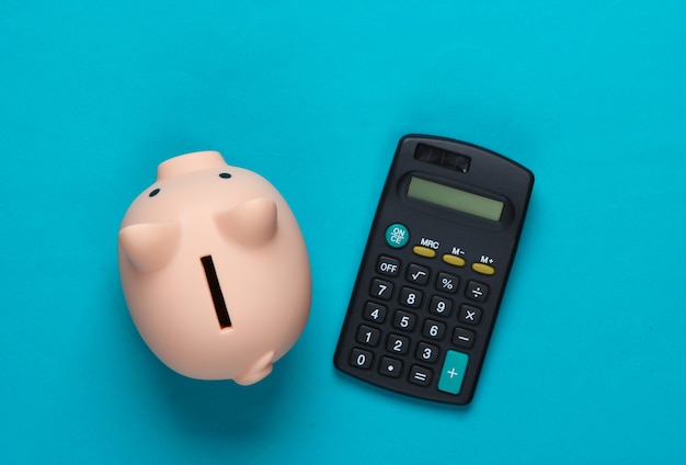 Piggy bank and calculator on blue