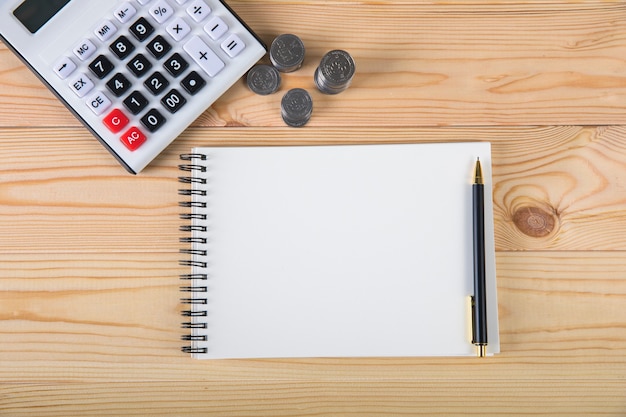 Piggy bank, calculator and coins on wooden surface