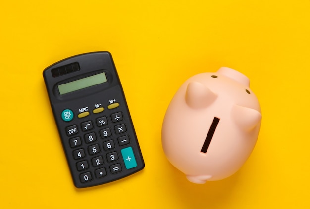 Piggy bank and calculator on yellow