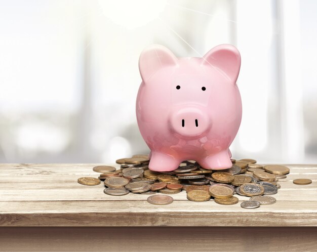 Piggy bank and coins on wooden table