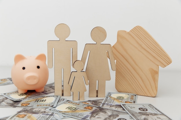 Photo piggy bank and figures of family with house on dollar banknotes.