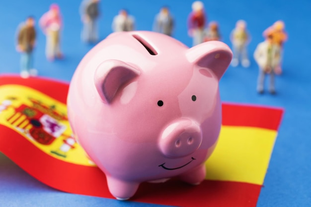 스페인 인구의 소득 개념에 대한 돼지 저금통 깃발과 플라스틱 장난감