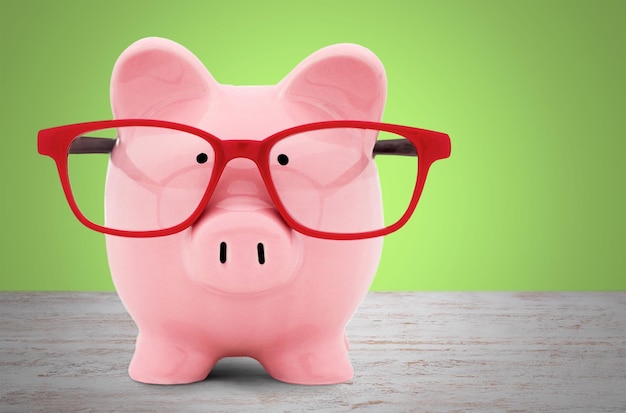 Piggy bank in glasses on background