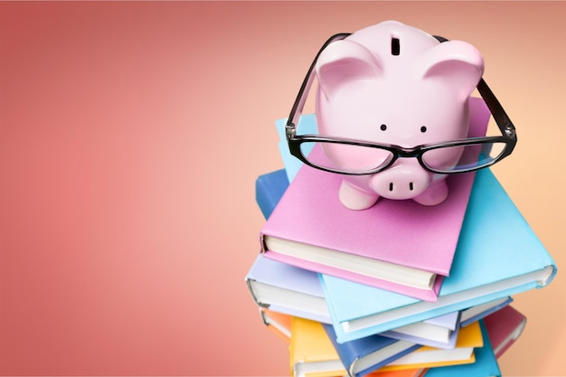 Piggy bank in glasses and books on background