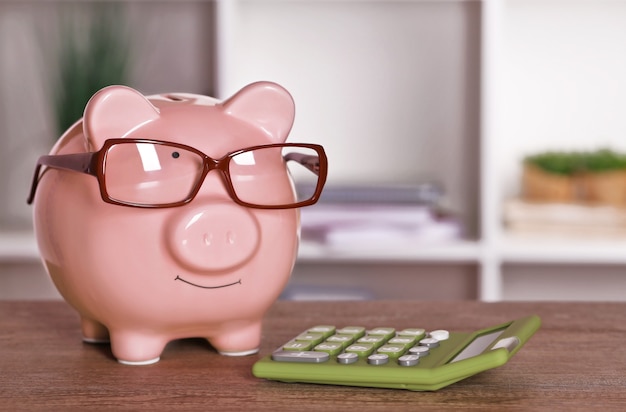 Piggy bank in glasses with calculator on home or office