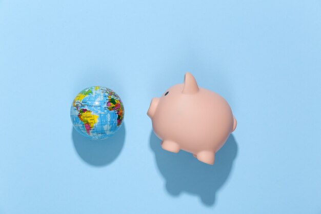 Piggy bank and globe on  blue sunny bright.