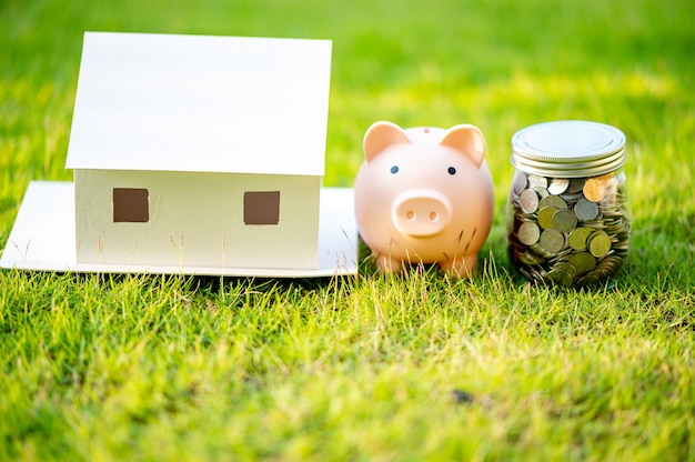 Копилка и модель дома, концепция Экономия денег на дом и недвижимость.