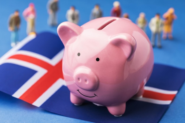 Piggy bank Icelandic flag and plastic toy men on a colored background