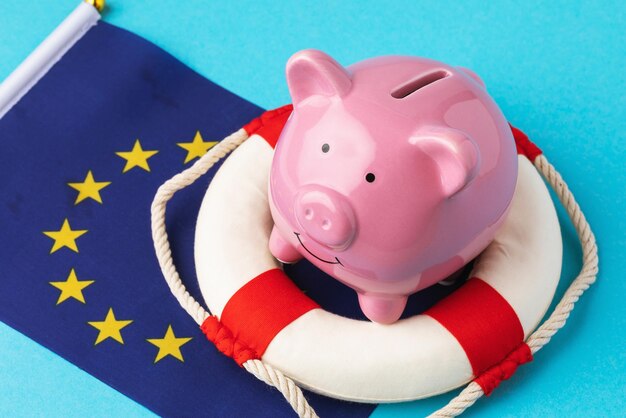 Piggy bank lifebuoy and flag on a blue background the concept of saving the EU economy