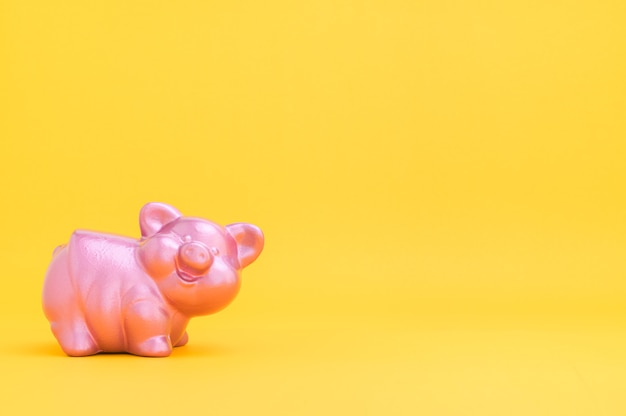 Piggy bank saving money against yellow background