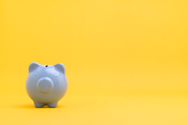 Piggy bank saving money against yellow background