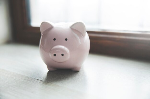 Photo a piggy bank sitting on a table in front of a window
