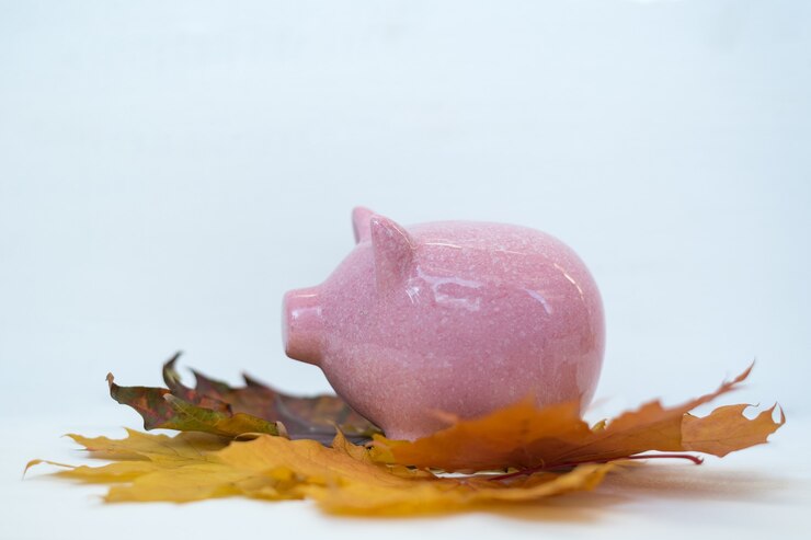 Foto piggy bank staande op herfstbladeren op witte achtergrond. herfst kortingen black friday concept.