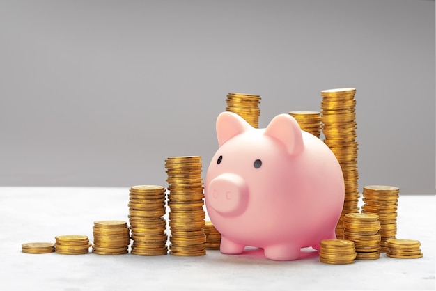 Piggy bank and a stack of gold coins on a gray background