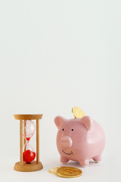 Photo piggy bank with bitcoin coins and hourglass on isolated white background