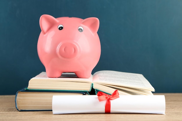 Piggy bank with books on blackboard background