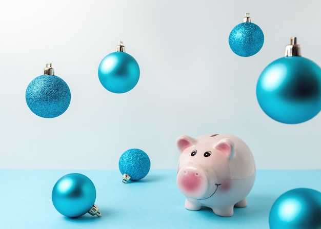 Piggy bank with Christmas decoration on blue table