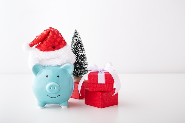 Piggy bank with christmas hat, gift and decor on white background