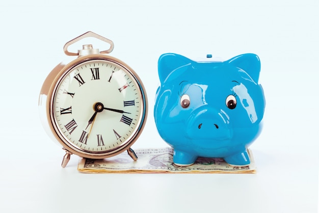 Piggy bank with clock on the heap of money.