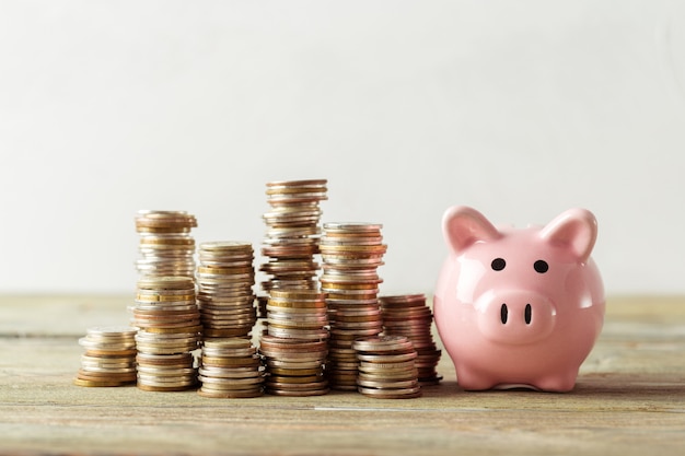 Piggy bank with coin on old wooden table