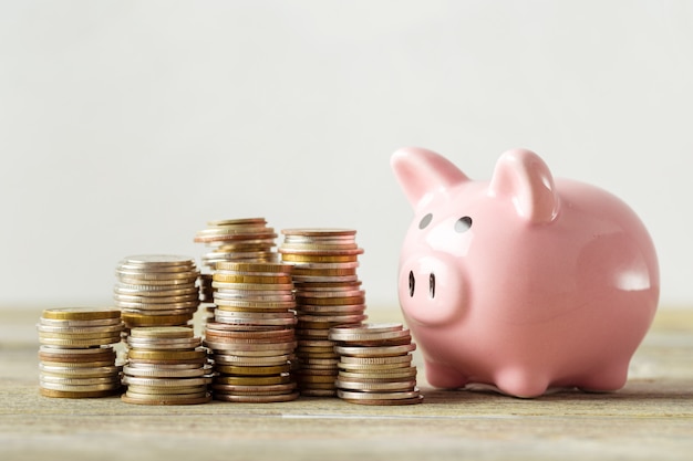 Piggy bank with coin on old wooden table