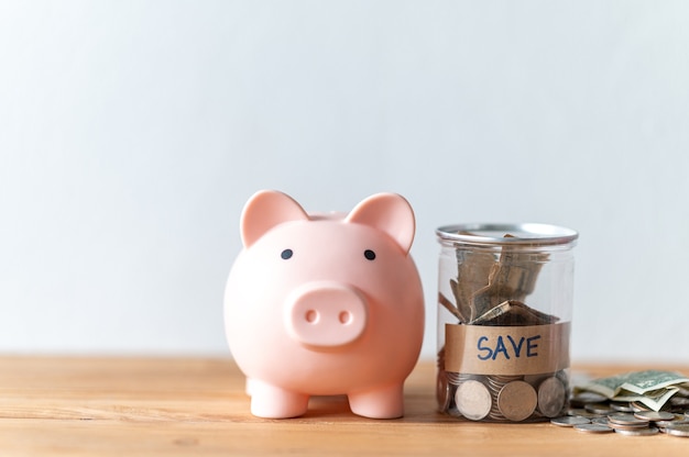 Piggy bank with coin on the wood table