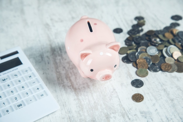 Piggy bank with coins and calculator on the desk