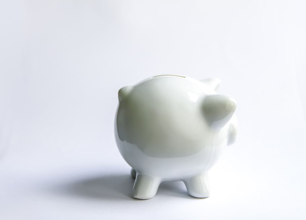Piggy bank with coins. White ceramic moneybox.