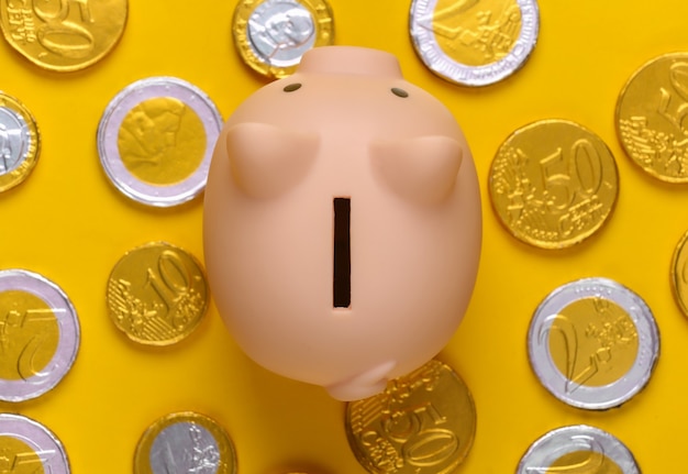 Piggy bank with coins on yellow