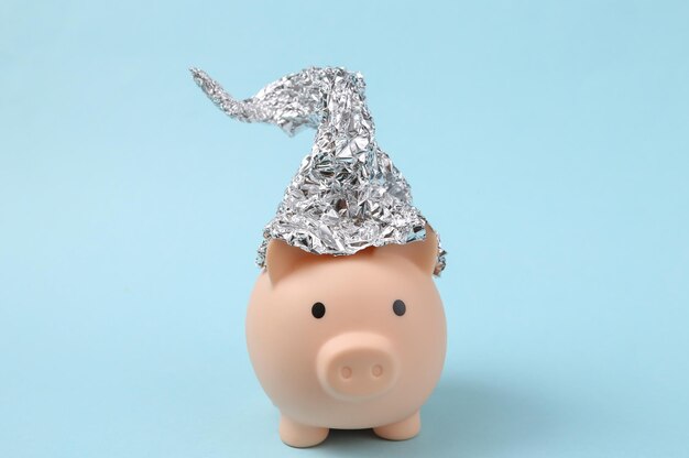 Piggy bank with foil hat on blue background