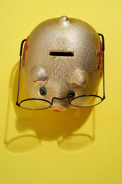 Photo piggy bank with glasses on yellow background