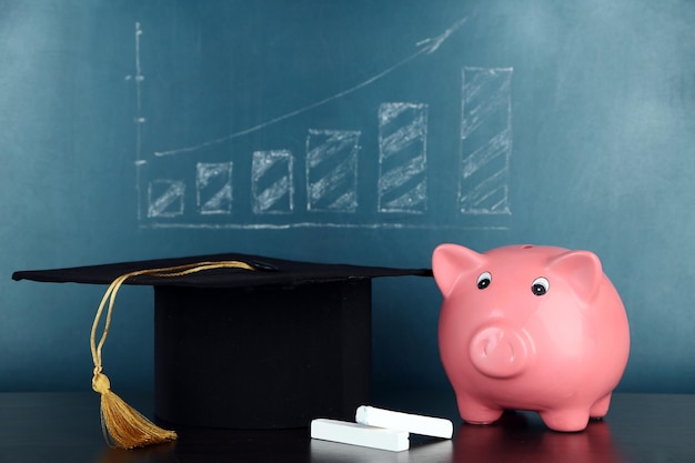 Photo piggy bank with grad hat on blackboard background