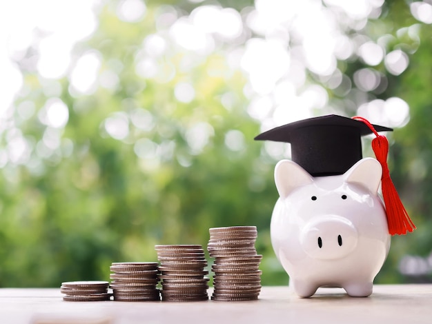 Piggy bank with graduation hat Glass bottle and stack of coins The concept of saving money for education student loan scholarship tuition fees in future