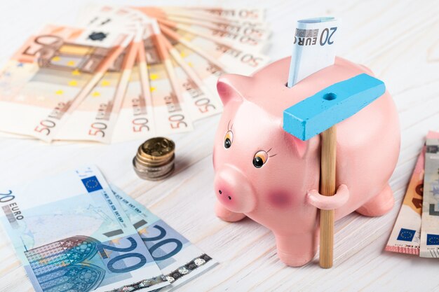 Piggy Bank with a hammer, Euro banknotes and coins