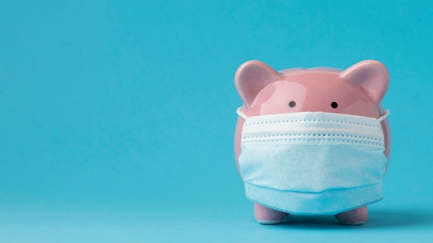 Piggy bank with medical mask and copy space