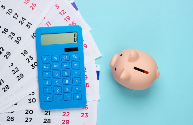 Piggy bank with a monthly calendar, calculator on a blue. payment of rental housing or loans