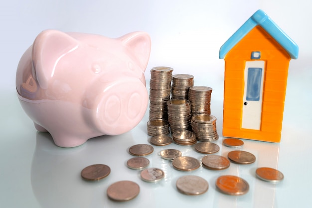 Piggy bank with small house and coin on white background