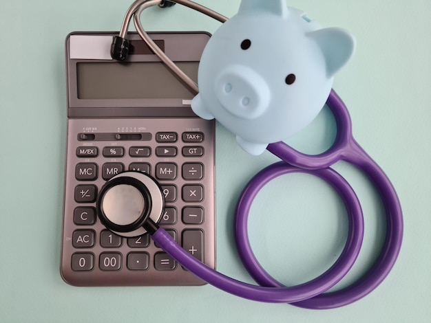 Piggy bank with stethoscope and calculator in clinic