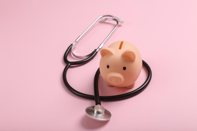 Foto piggy bank con stetoscopio su sfondo rosa vista superiore