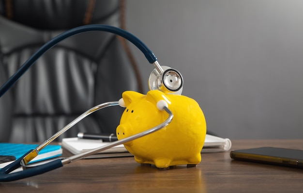 Piggy bank with stethoscope on the wooden table