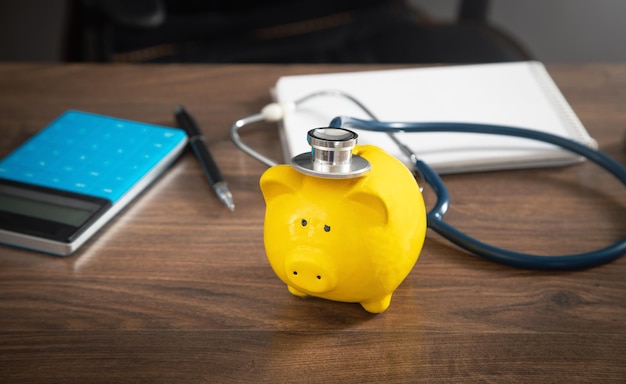 Piggy bank with stethoscope on the wooden table